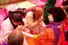 Two mendhi wallahs apply the henna to the hands of guests.
