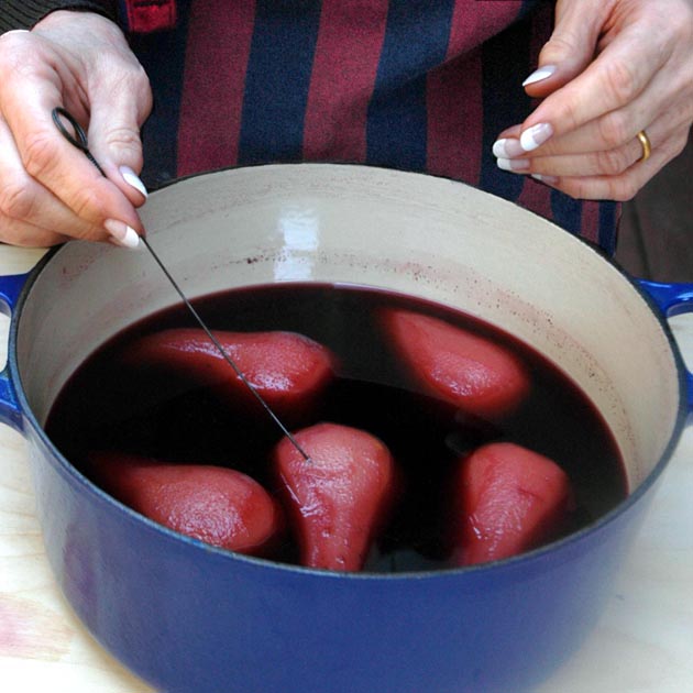 Testing poached pears for doneness.